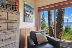 A room with a large window offering a view of trees and a body of water. - Shoreline Vista | 180° Lake Views | Pet-Friendly | 2 Master Suites (Carnelian Bay)
