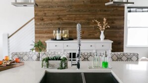 Una cocina moderna con un grifo de acero inoxidable, una encimera blanca y una pared de madera.