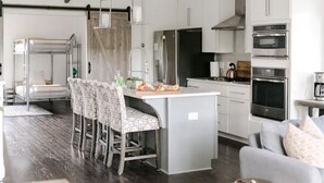 Una cocina moderna con una isla central, electrodomésticos de acero inoxidable y un comedor con sillas estampadas.