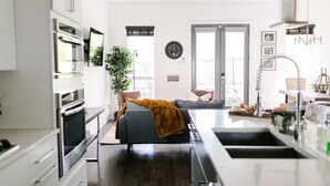 Una cocina moderna con armarios blancos, horno integrado y un ventanal grande.