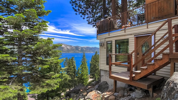 A cabin with a wooden staircase leading to a deck, overlooking a lake and mountains. - Stunning Views at Stargazer Lakefront Studio! (Incline Village)