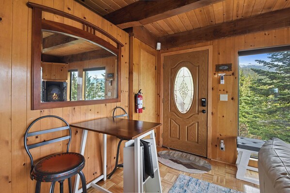 A wooden cabin interior with a dining table, a chair, a fire extinguisher, and a door with a glass panel. - Stunning Views at Stargazer Lakefront Studio! (Incline Village)