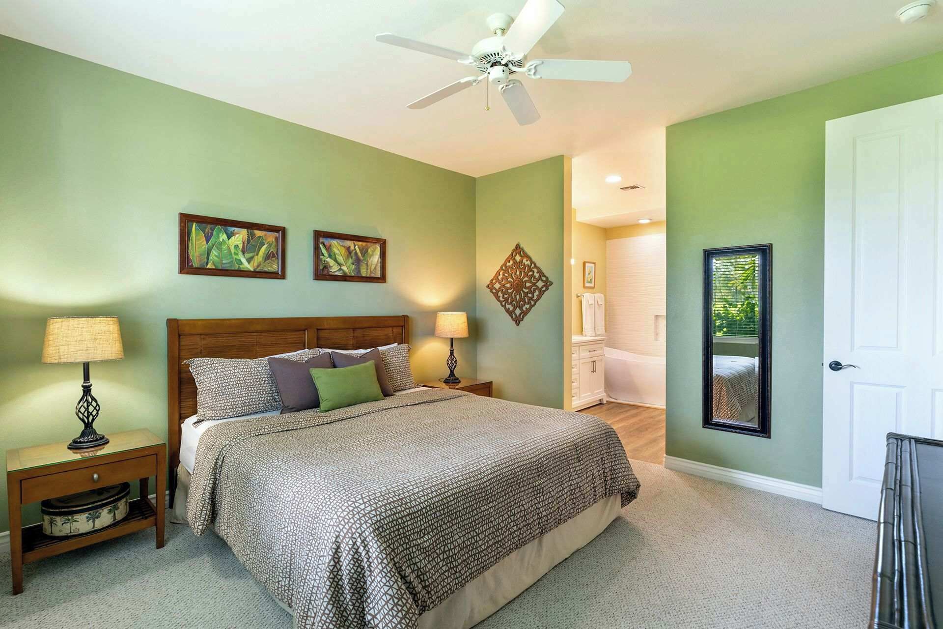 Ein Schlafzimmer mit einem Bett, zwei Nachttischen, einem Deckenventilator und Kunstwerken an den Wänden.