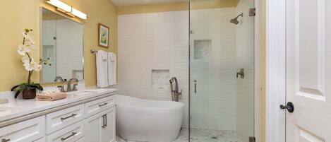 A bathroom with a white bathtub, a glass-enclosed shower, and a vanity with a mirror and sink.