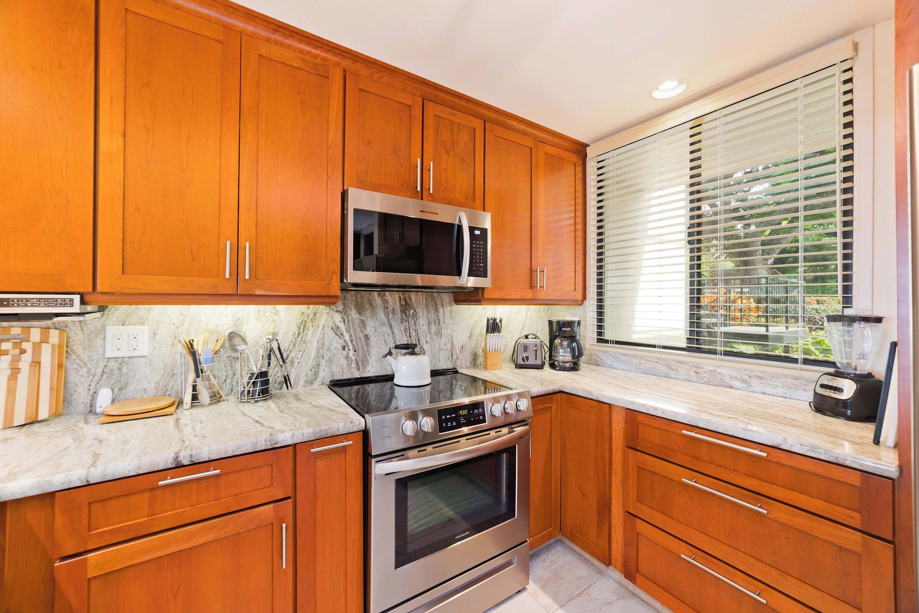 Una cocina moderna con armarios de madera, electrodomésticos de acero inoxidable y una ventana con persianas.