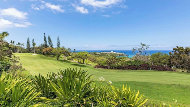 A golf course with a view of the ocean and a hotel in the background. - Country Club Villas Golf, A/C & Oceanview (Kailua-Kona)