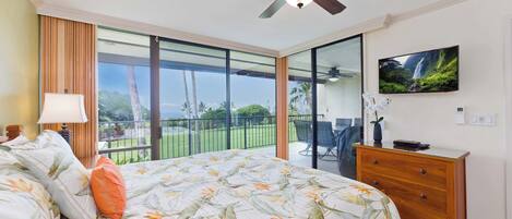 Une chambre à coucher comprenant un lit, une commode, un téléviseur et un balcon donnant sur l’extérieur.