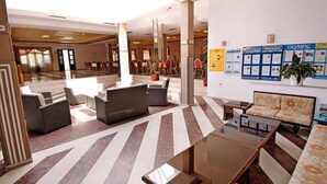 A spacious lobby with a striped floor, seating areas, and a wall with Olympic-themed posters. - Elena Mare (Lesvos)