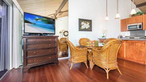 Ein Essbereich mit Korbstühlen, einem Holztisch und einem Fernseher auf einer Kommode.