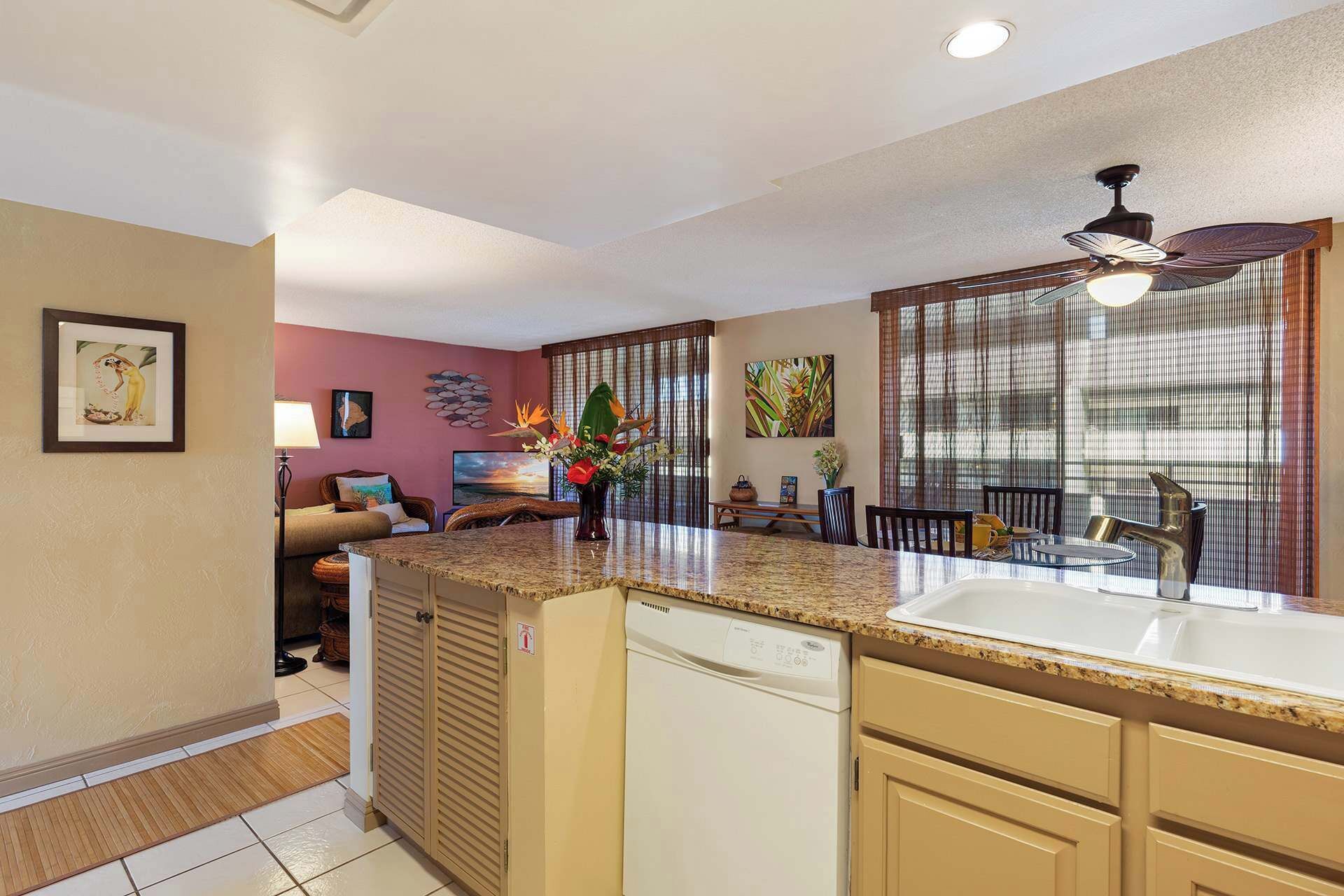 A modern kitchen with granite countertops, a dishwasher, and a dining area with a table and chairs.