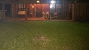 Ein hölzernes Scheunenhaus mit Veranda, zwei Stühlen und einem Tisch.