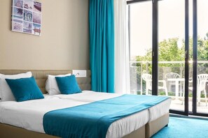 A hotel room with a bed, a window with a view of the outdoors, and a wall with a beach-themed poster. - Arena Mar Hotel & SPA - All Inclusive (Varna)