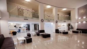 A spacious lobby with a high ceiling, multiple seating areas, and a reception desk. - Arena Mar Hotel & SPA - All Inclusive (Varna)