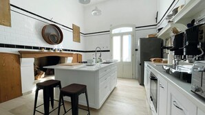 A modern kitchen with white cabinetry, a central island, bar stools, and a coffee machine. - Rural mansion from the 1700s with swimming pool, hot tub and solarium. (Nardò)