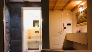 A room with a bed, a bathroom with a sink and mirror, and a painting on the wall. - Rural mansion from the 1700s with swimming pool, hot tub and solarium. (Nardò)
