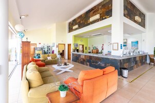 Un vestíbulo amplio con mostrador de recepción, zona de estar y vistas al exterior.
