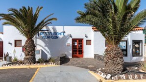 Un edificio blanco con puerta roja y un letrero que dice 'RESTAURANTE MIRADOR'.