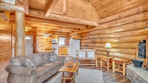A log cabin interior with a sofa, coffee table, and dining area. - Sky Views - 2BR/New Hot Tub/New Firepit/Grill/Sleeps 8 (Gatlinburg)