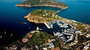 Vista aérea de uma área costeira com um porto de iates, barcos e edifícios.