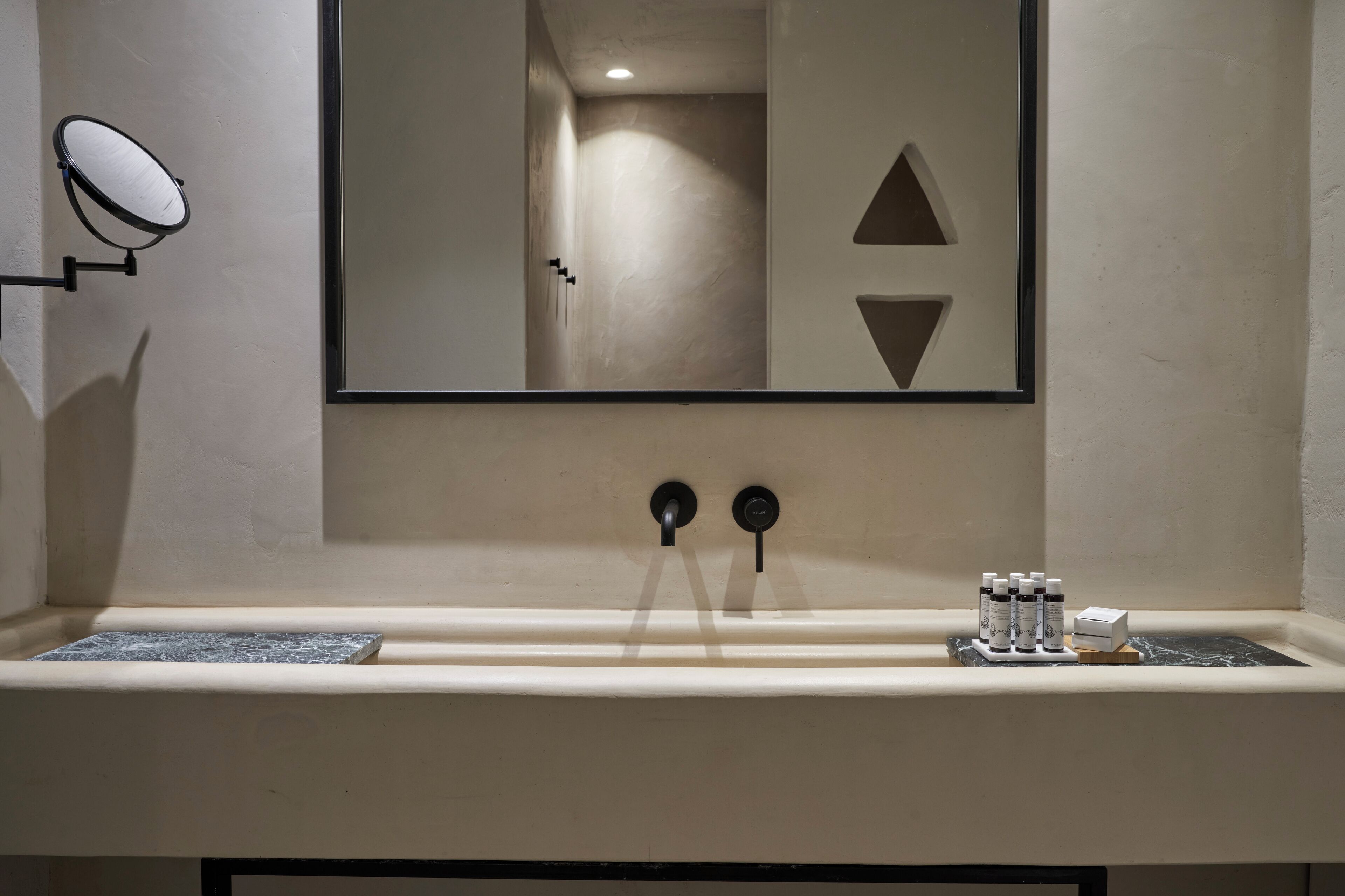 A bathroom with a large mirror, a sink with a marble countertop, and a small shelf with toiletries.