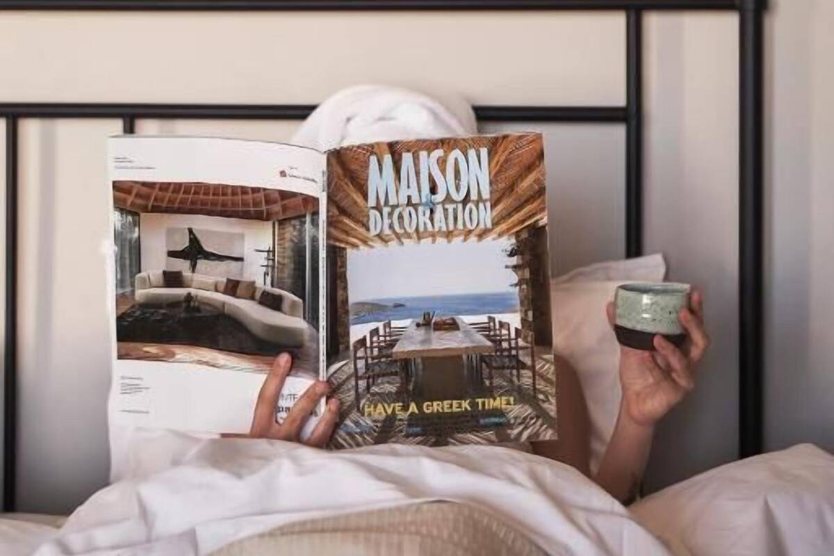 A person lying in bed, reading a book titled 'MAISON DECORATION'.