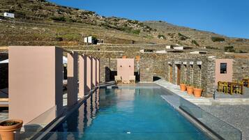 A pool area with stone walls, potted plants, and outdoor seating.