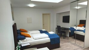 A modern hotel room with a bed, a desk, a chair, and a TV. - Studio Apartment 30m2 (Bad Homburg vor der Höhe)