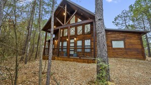 Una cabaña de madera con ventanas amplias, rodeada de árboles.