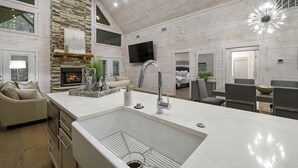 Una cocina moderna con una isla grande, una pared de acento de piedra y una chimenea.