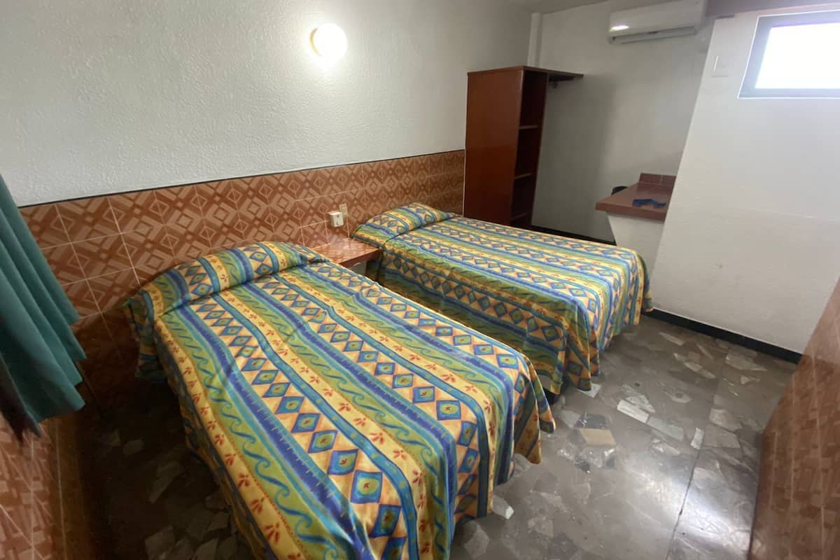 A room with two beds, a small table, a wardrobe, and a window.