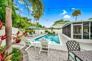 Un jardin avec une piscine, des chaises longues et un patio couvert.
