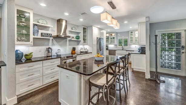 A modern kitchen with white cabinetry, a central island with bar stools, and a decorative door with geometric patterns. - Private Heated Pool, walk to St Armand's! Perfect for families! (Lido Key)