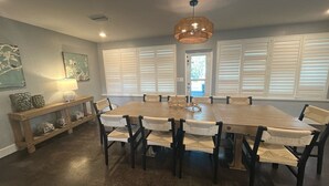A dining room with a large wooden table, six chairs, a bench, and a hanging light fixture. - Private Heated Pool, walk to St Armand's! Perfect for families! (Lido Key)