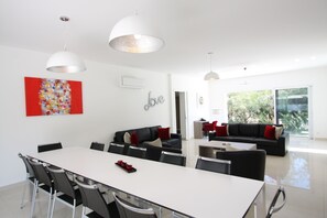 A modern living space with a dining area, sofas, and a large window. - Luxury Modern Villa with 6 Bedrooms featuring a Private Pool, Garden, Parking & SPA (Calvi)