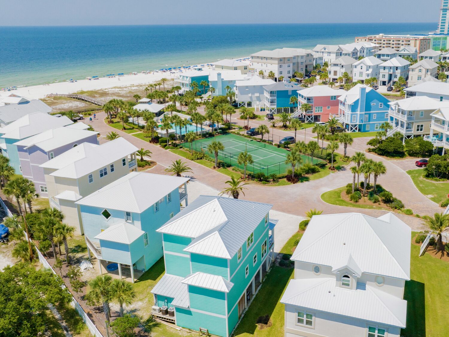 A coastal resort with beachfront villas, a tennis court, and a boardwalk.
