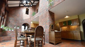 Une cuisine spacieuse avec des murs en briques, des armoires en bois et un coin repas comprenant une table et des chaises.