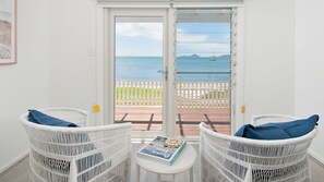 Enjoy ocean views from the comfort of this serene room, featuring a pair of wicker chairs and a small table.