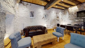 A rustic living room with exposed stone walls, a leather sofa, and a wooden coffee table.