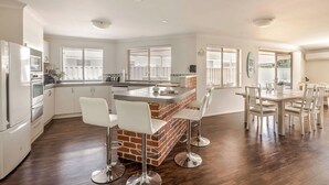Une cuisine moderne dotée d’un îlot central, de tabourets de bar et d’un coin repas avec une table et des chaises en bois.