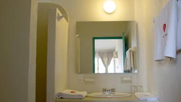 Un bagno con lavandino, specchio e portasciugamani.
