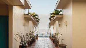 A corridor with potted plants and a tiled floor leading to a gate. - Las Arenas Bungalows Melaque (San Patricio Melaque)