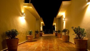 A corridor with potted plants and wall-mounted lights. - Las Arenas Bungalows Melaque (San Patricio Melaque)