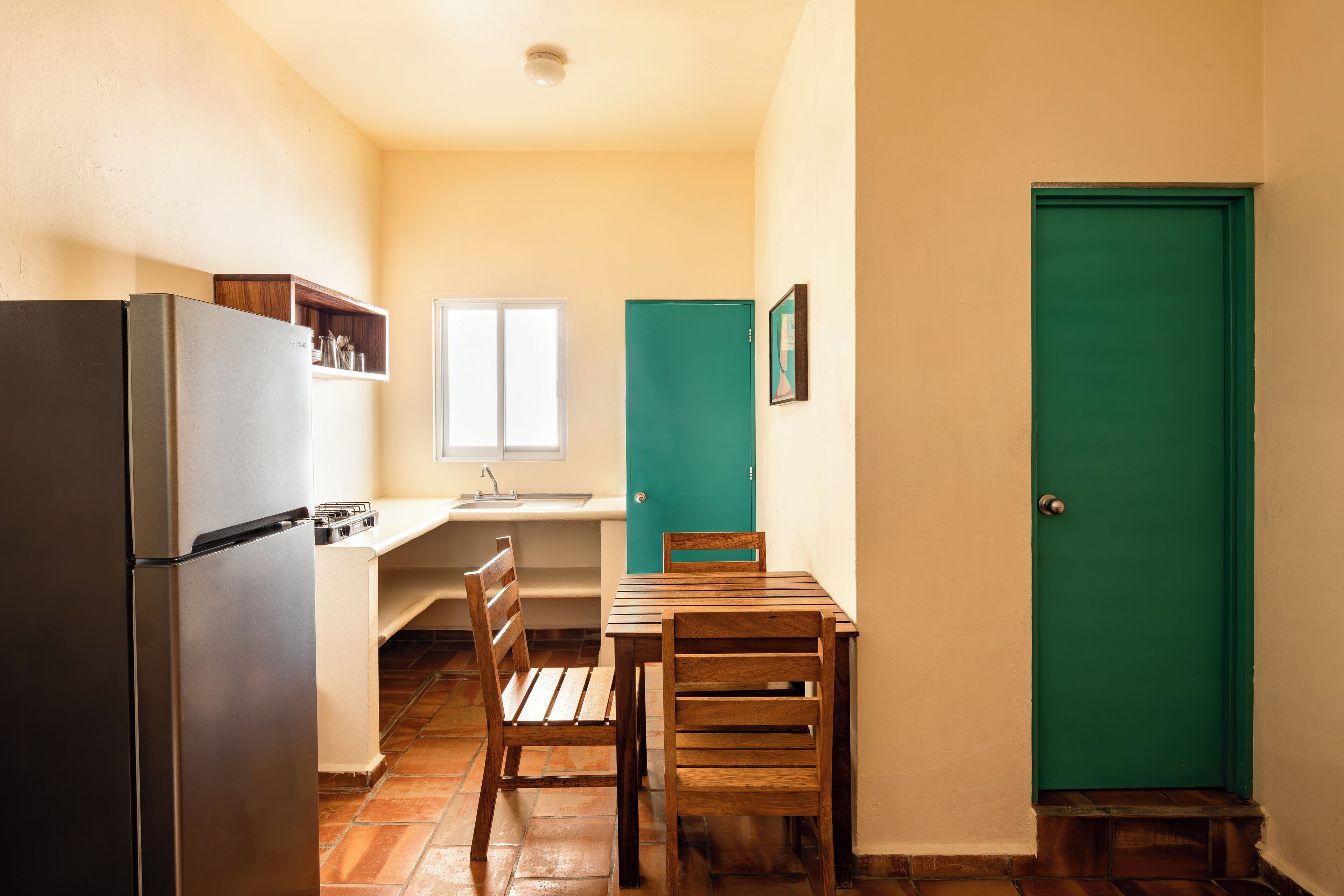 Una cocina compacta con refrigerador, un lavamanos y un ventanal.