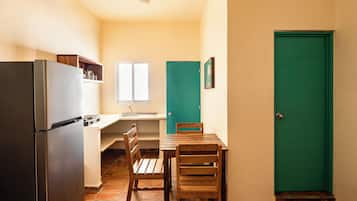 Una cocina compacta con refrigerador, un lavamanos y un ventanal.