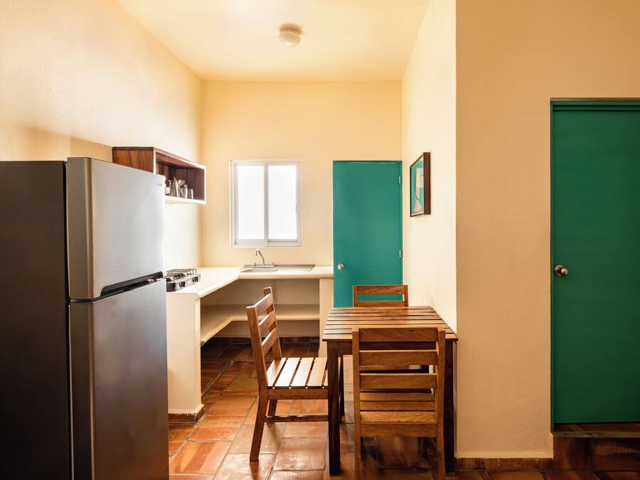 Una cocina compacta con refrigerador, un lavamanos y un ventanal.