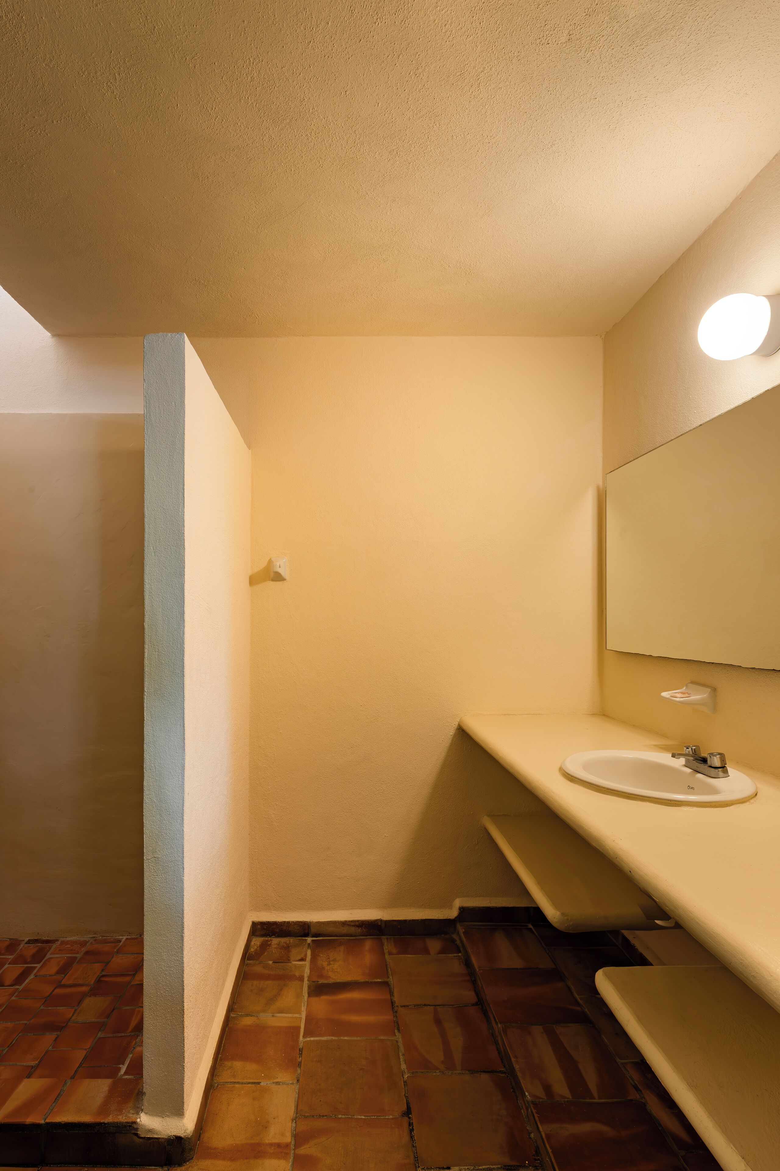 A bathroom with a white sink, a mirror, and a light fixture.