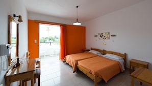 A bedroom with two beds, a wooden table, a desk, and a balcony with a view. - Laura (Kos)
