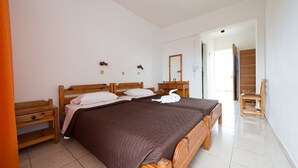 A bedroom with a large bed, wooden headboard, two bedside tables, a mirror, and a chair. - Laura (Kos)