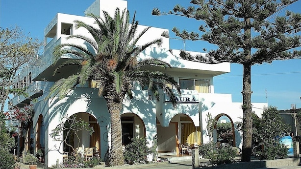 A building with a white facade, multiple balconies, and arched doorways. - Laura (Kos)