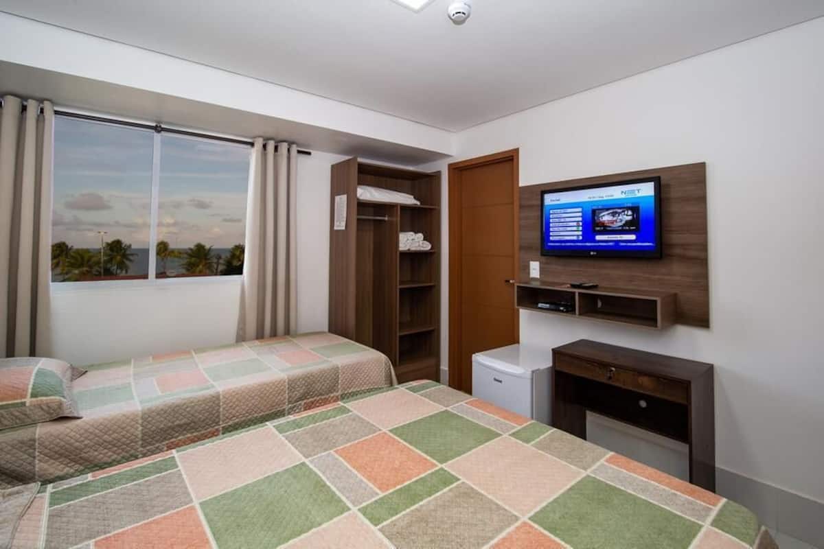 A hotel room with two beds, a TV, a desk, and a wardrobe.